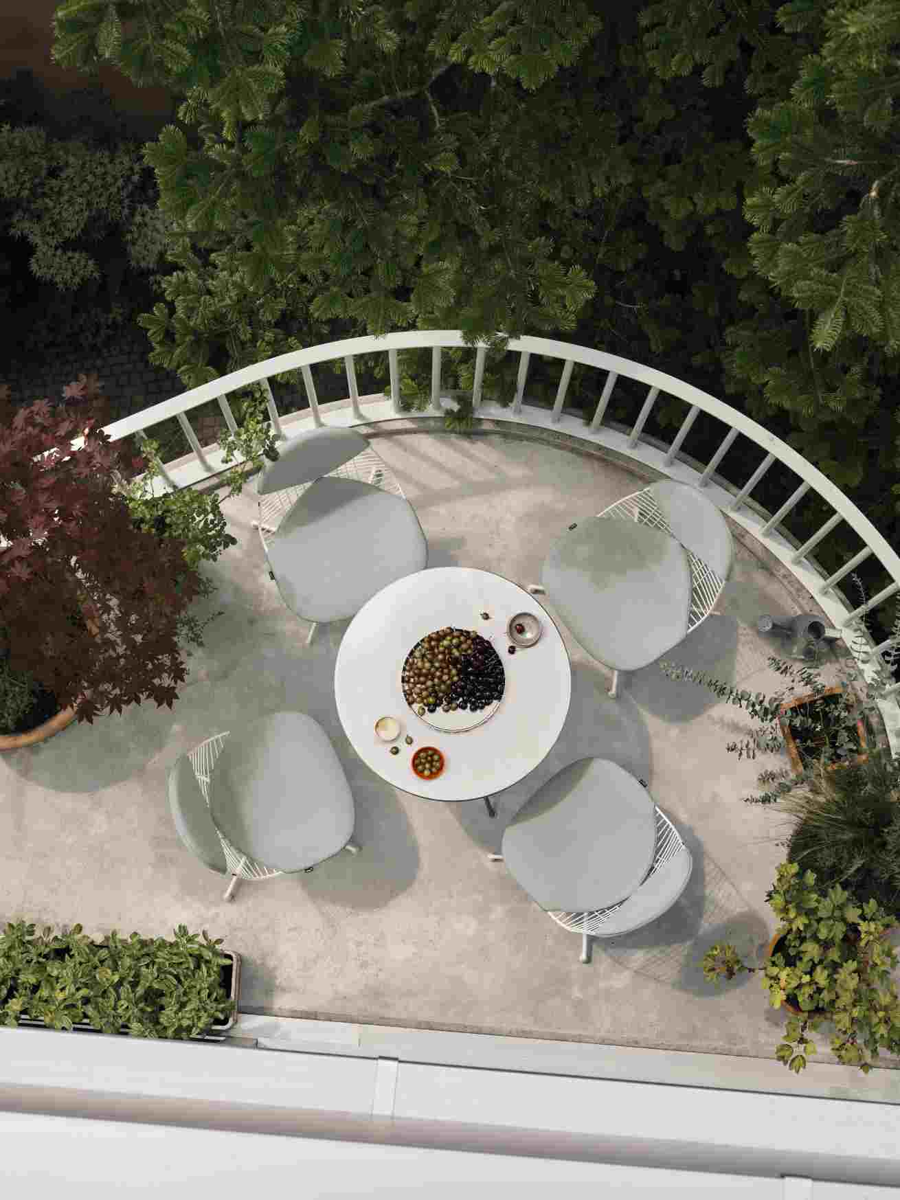 Draufsicht: Vitra Wire Chair Bikini Outdoor Sitzgruppe mit Tisch und Oliven auf Balkon.