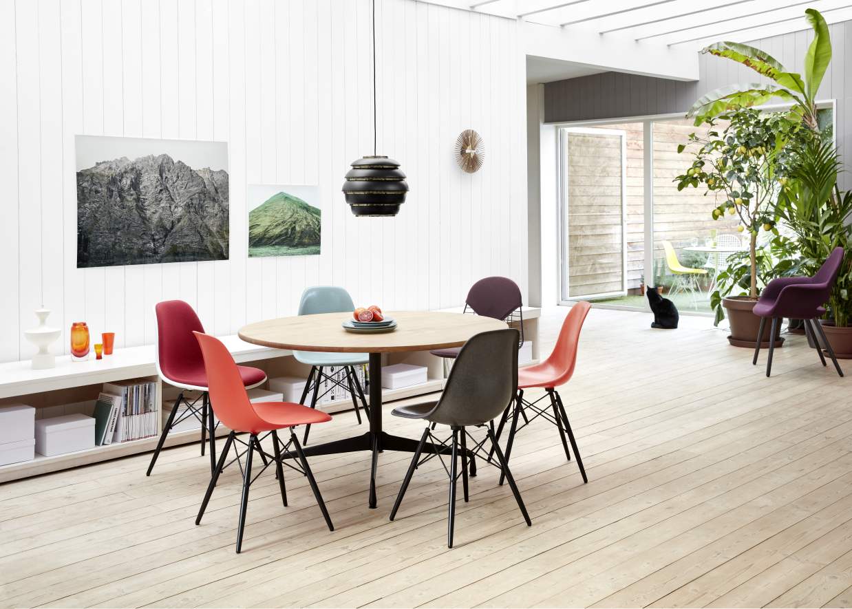 Esszimmer mit Vitra Eames Stühlen, Holztisch und einer Popsicle Clock Wanduhr im Hintergrund.