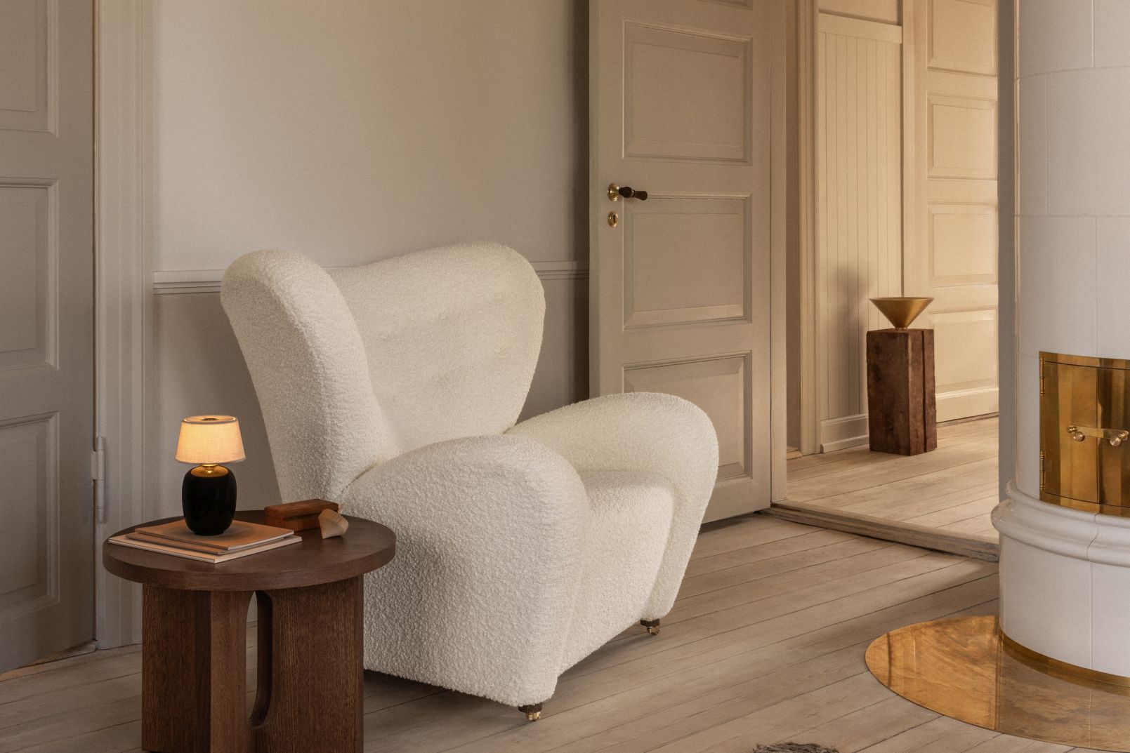 Nahaufnahme eines Wohnzimmers mit Audo Copenhagen Sessel, Beistelltisch mit Lampe und dekorativer Taper Schale.