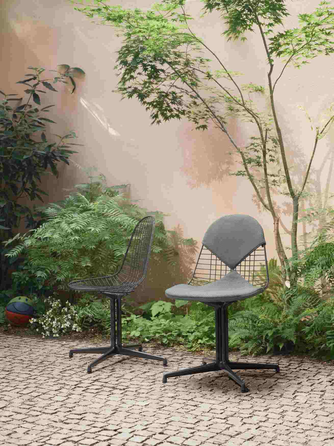 Vitra Wire Chair Bikini Outdoor Stühle in Schwarz und Grau vor grüner Pflanzenwand.
