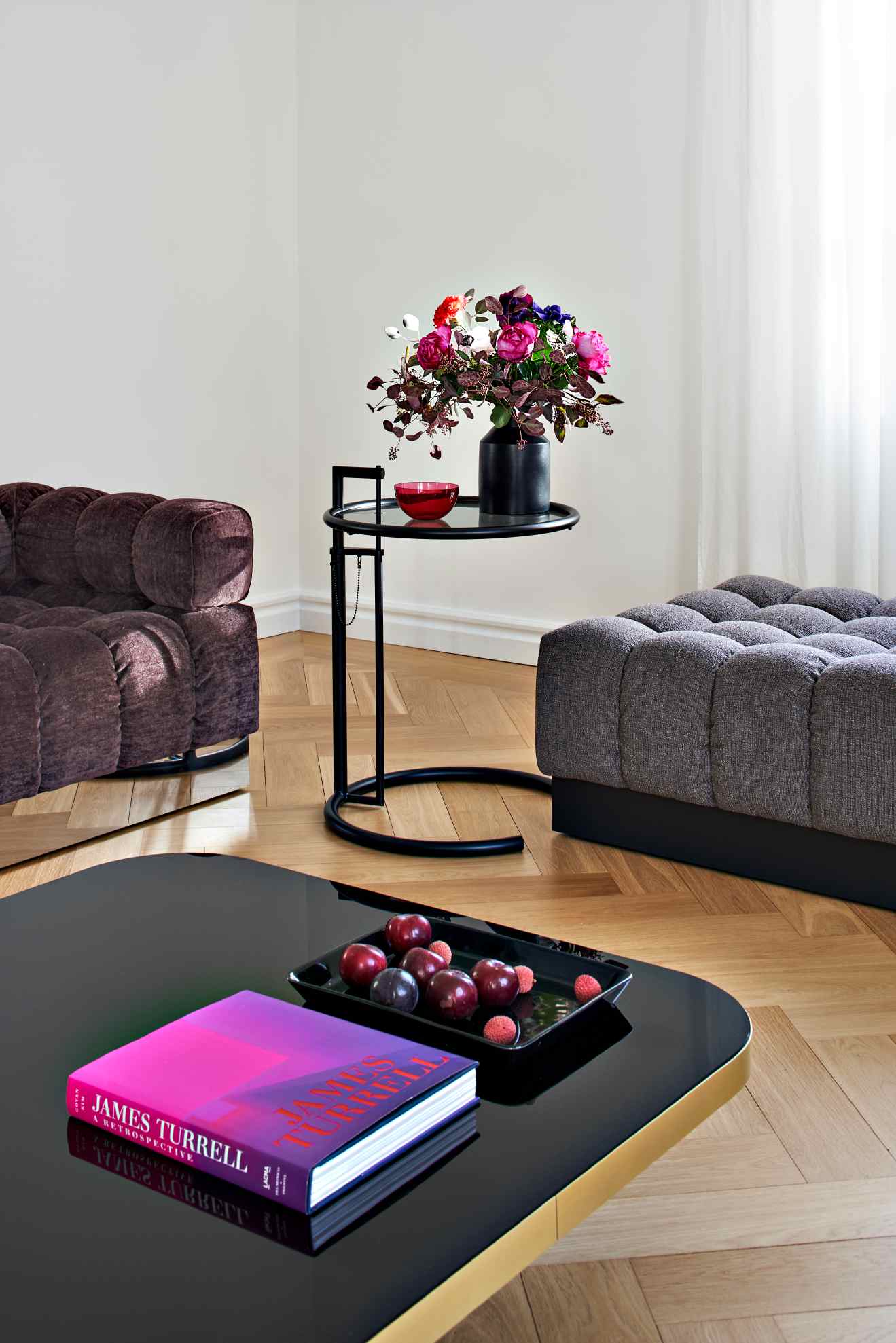 ClassiCon Bow Coffee Table No. 4: Schwarzer Couchtisch mit Buch und Obst, modernes Wohnzimmer-Interieur.