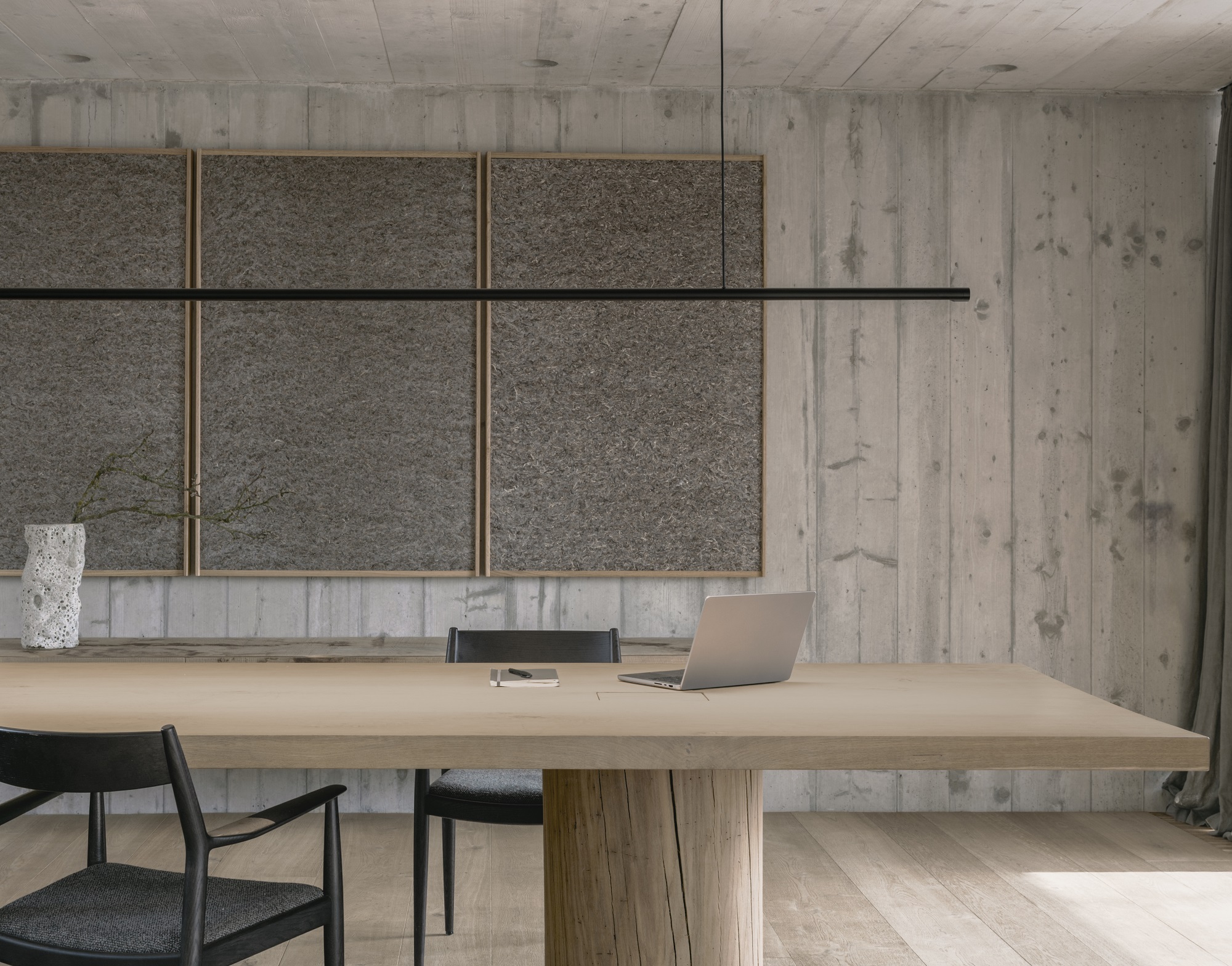 Moderne Büroeinrichtung mit w181 S2 Linier Pro Pendelleuchte über Holztisch, Laptop und Stühlen in Betonumgebung.