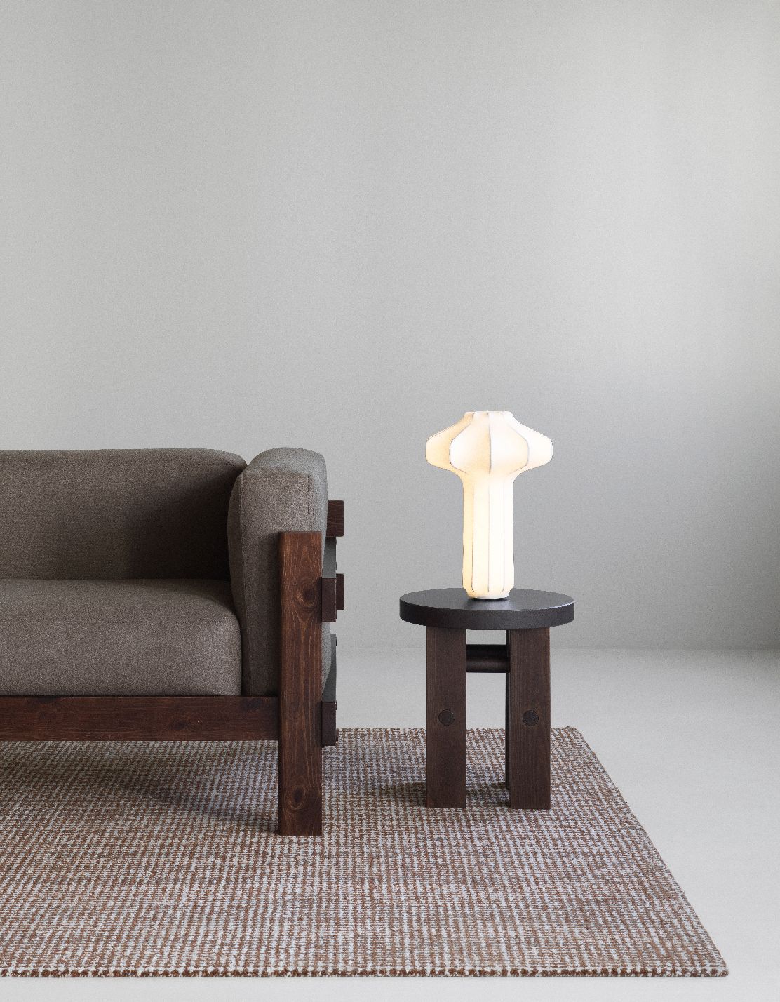 Normann Copenhagen Kube Sofa, graues Stoffsofa mit Holzrahmen, Tisch mit Lampe und Teppich.