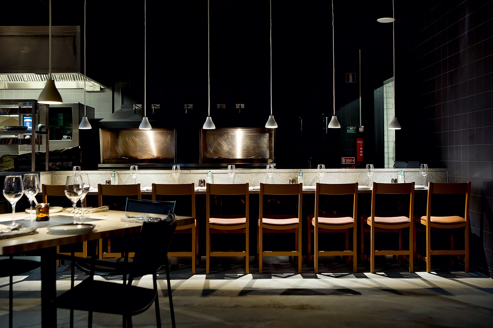 Innenaufnahme eines Restaurants mit mehreren w131 Bell Pendelleuchten von wästberg über einer langen Theke.
