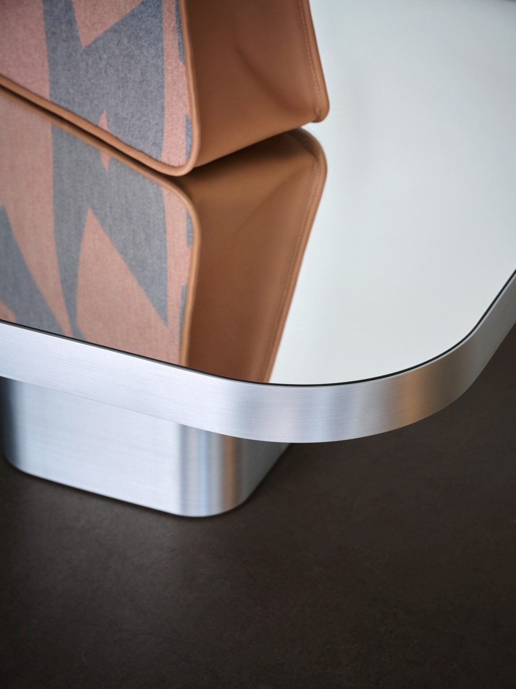 Detailaufnahme des ClassiCon Bow Coffee Table: Moderner Couchtisch mit spiegelnder Tischplatte und silbernem Metallfuß.
