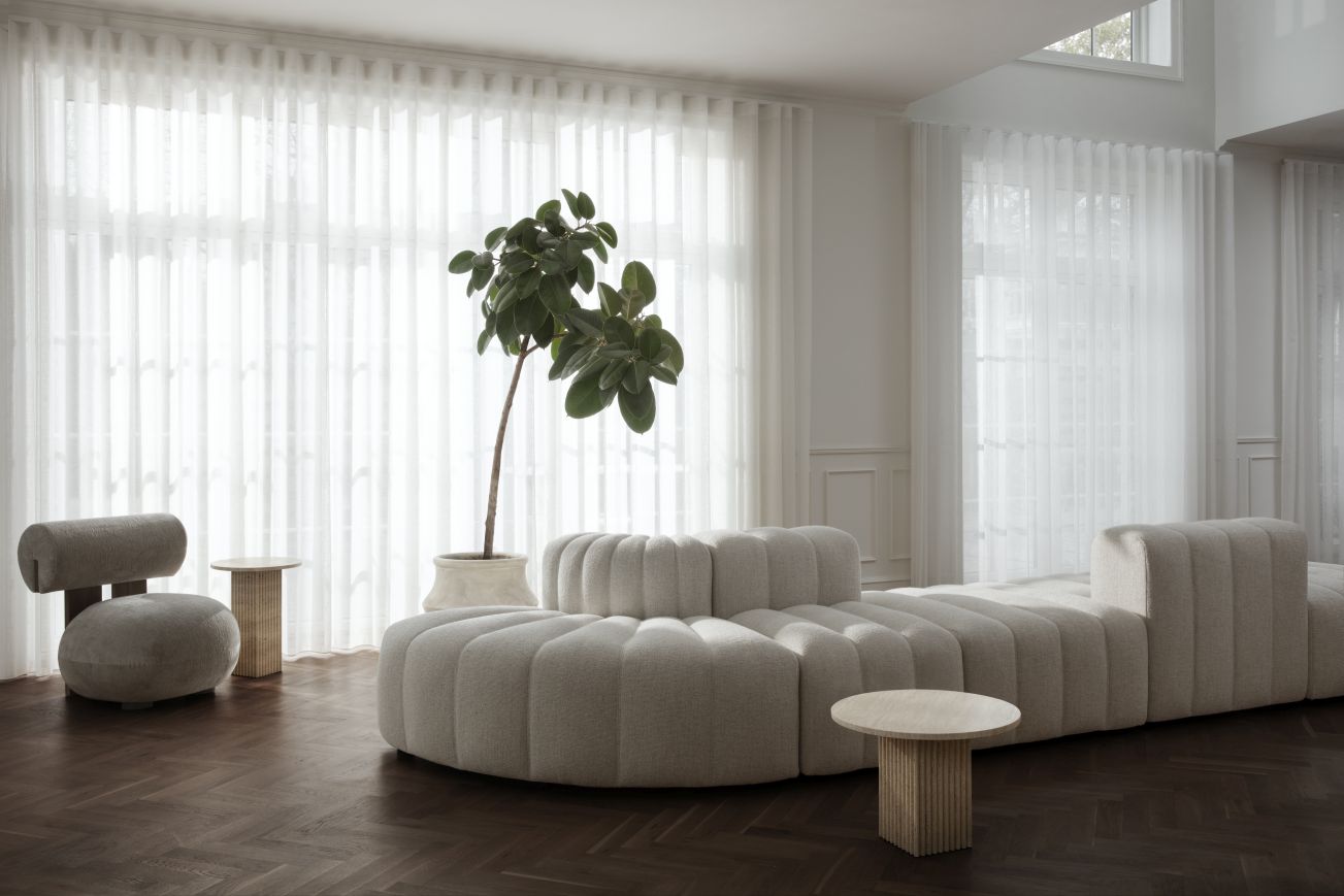 Heller Wohnraum mit Hippo Lounge Sessel von NORR11, modularem Sofa und Beistelltischen auf dunklem Parkett.