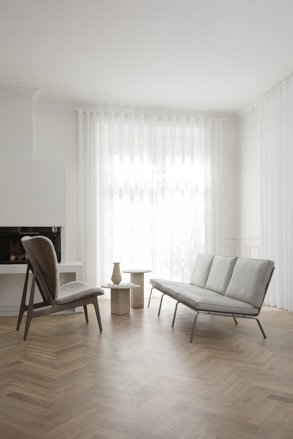 Helles Wohnzimmer mit NORR11 Man Sofa, Sessel und Beistelltischen auf Parkettboden.