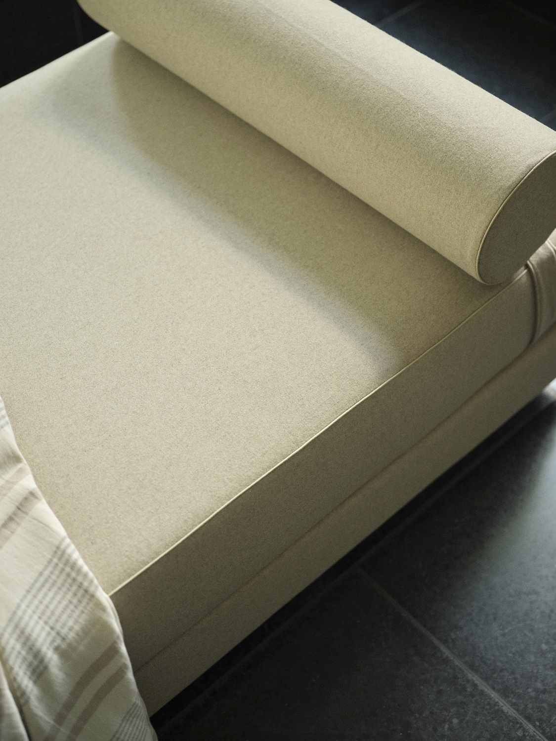 Nahaufnahme des beigen Lubi Daybeds mit Rollkissen und karierter Decke, Schlafsofa für Wohnzimmer.