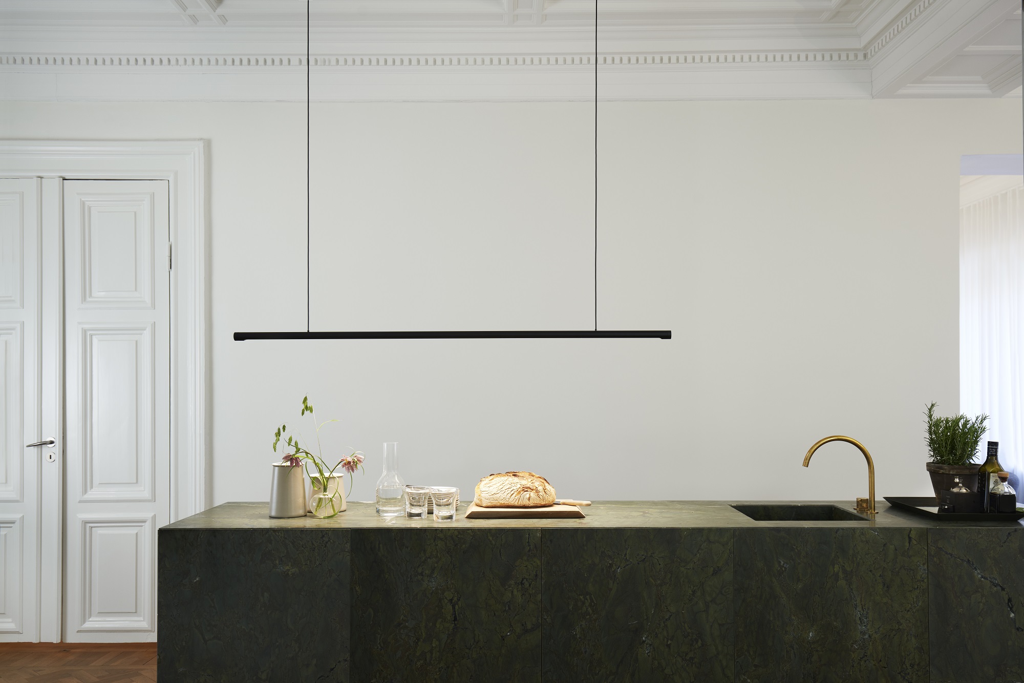 Moderne w181 Linier Pendelleuchte von wästberg in Schwarz über Küchentisch mit Speisen und Getränken.