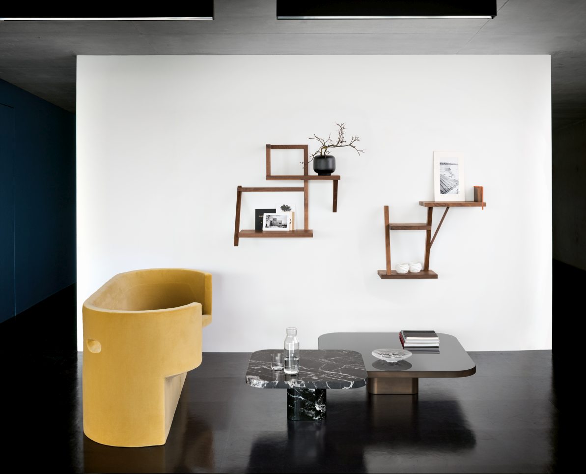 ClassiCon Bow Coffee Table No. 2 Couchtisch im modernen Wohnzimmer mit gelbem Sessel und Wandregalen.