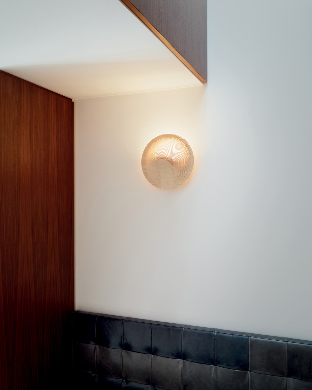 Illan Wandleuchte von Luceplan, runde Holzlampe an weißer Wand, indirekte Beleuchtung.