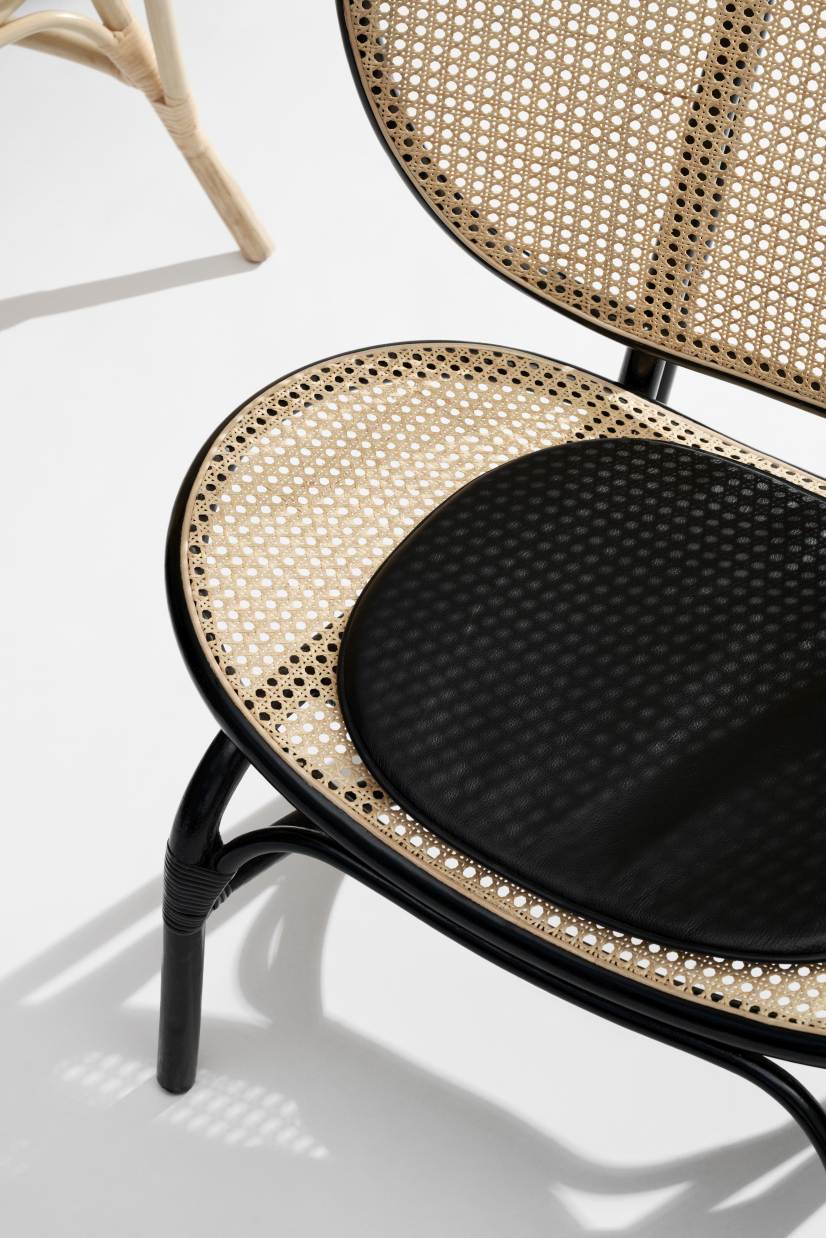 Detailaufnahme des NORR11 Nomad Chair Sessels mit schwarzem Lederkissen und Wiener Geflecht.
