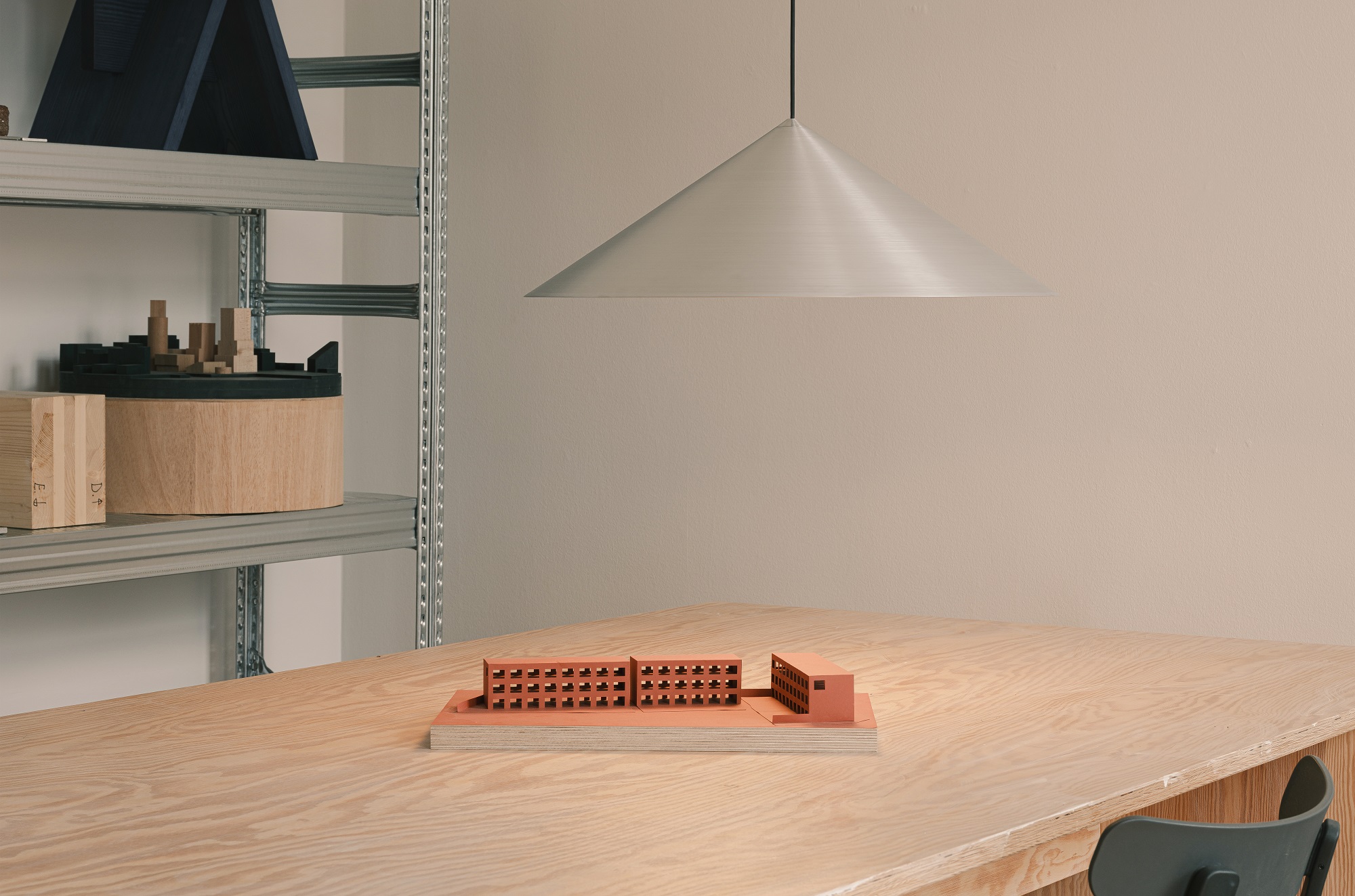 w221 S3 Medium Pendelleuchte von wästberg, Kegelförmiger Lampenschirm aus Aluminium über Holztisch mit Architekturmodell.