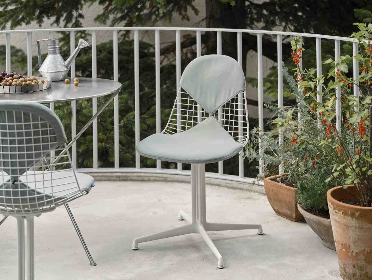 Vitra Wire Chair Bikini Outdoor in Weiß mit hellgrauen Kissen auf einer Terrasse.