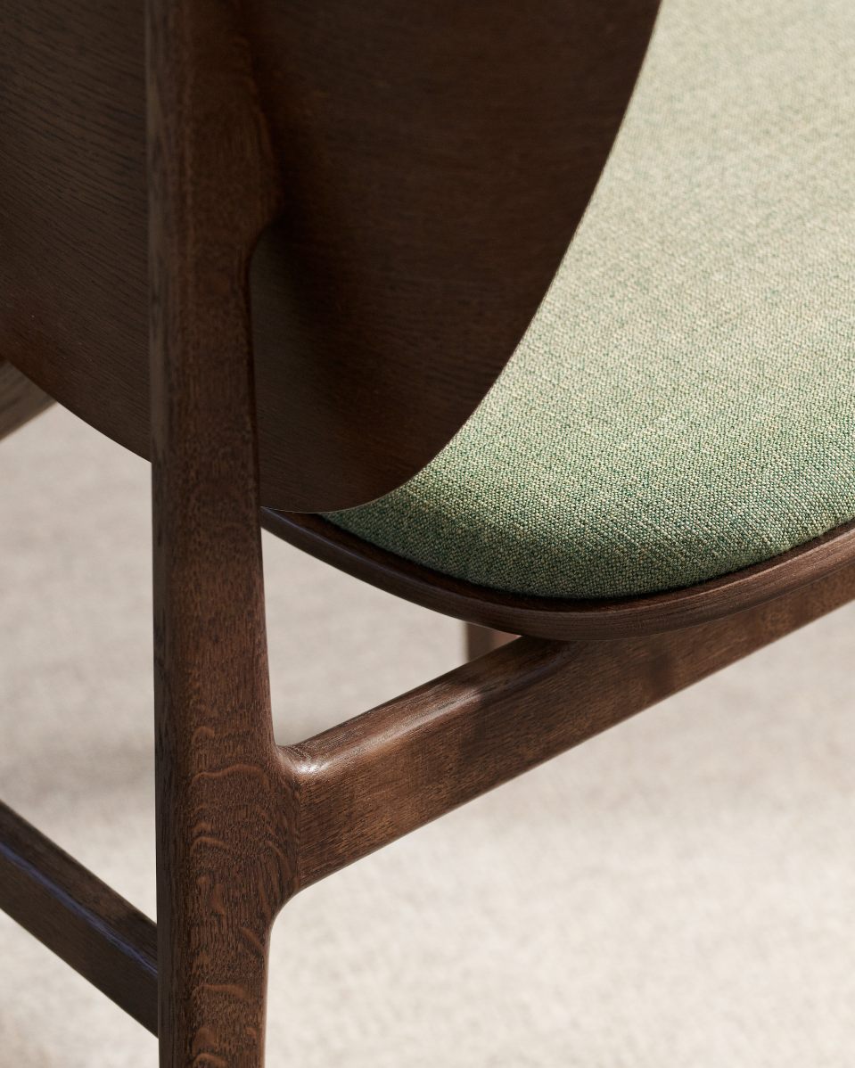 Detailaufnahme vom NORR11 Elephant Dining Chair Stuhl mit grüner Polsterung und dunklem Holzrahmen.