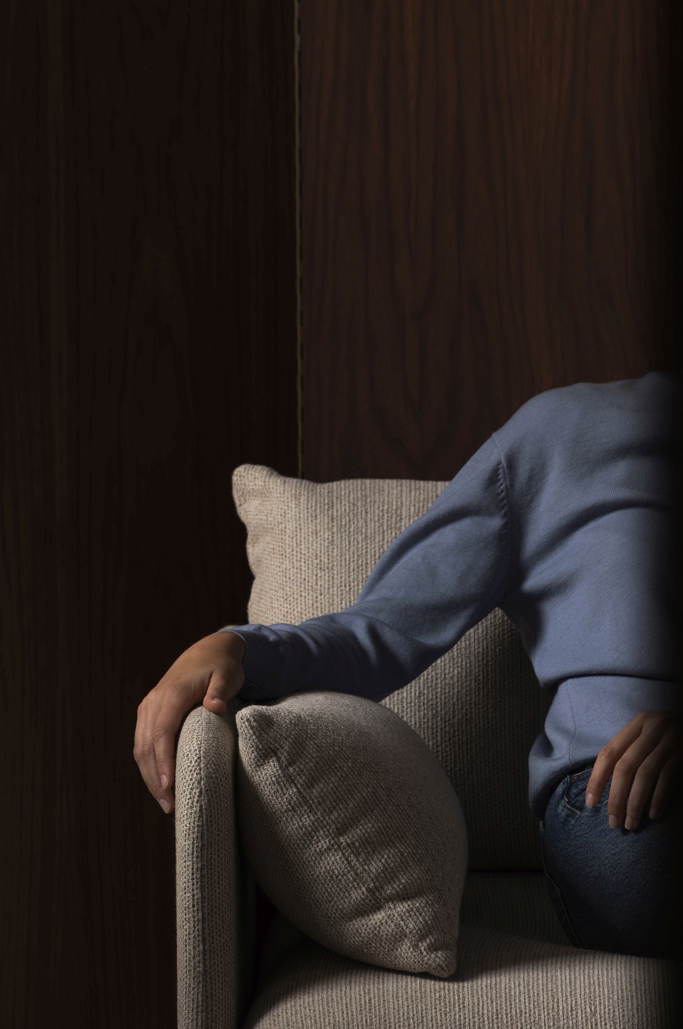 Detailaufnahme einer Person, die auf einem beigen Audo Copenhagen Sofa sitzt, mit Kissen und Jeans.