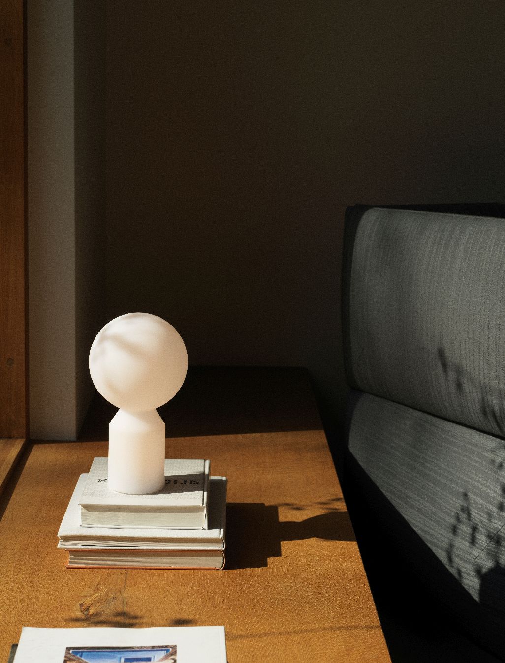 Nahaufnahme der Yo Lamp Small Tischleuchte von Normann Copenhagen auf einem Stapel Bücher.
