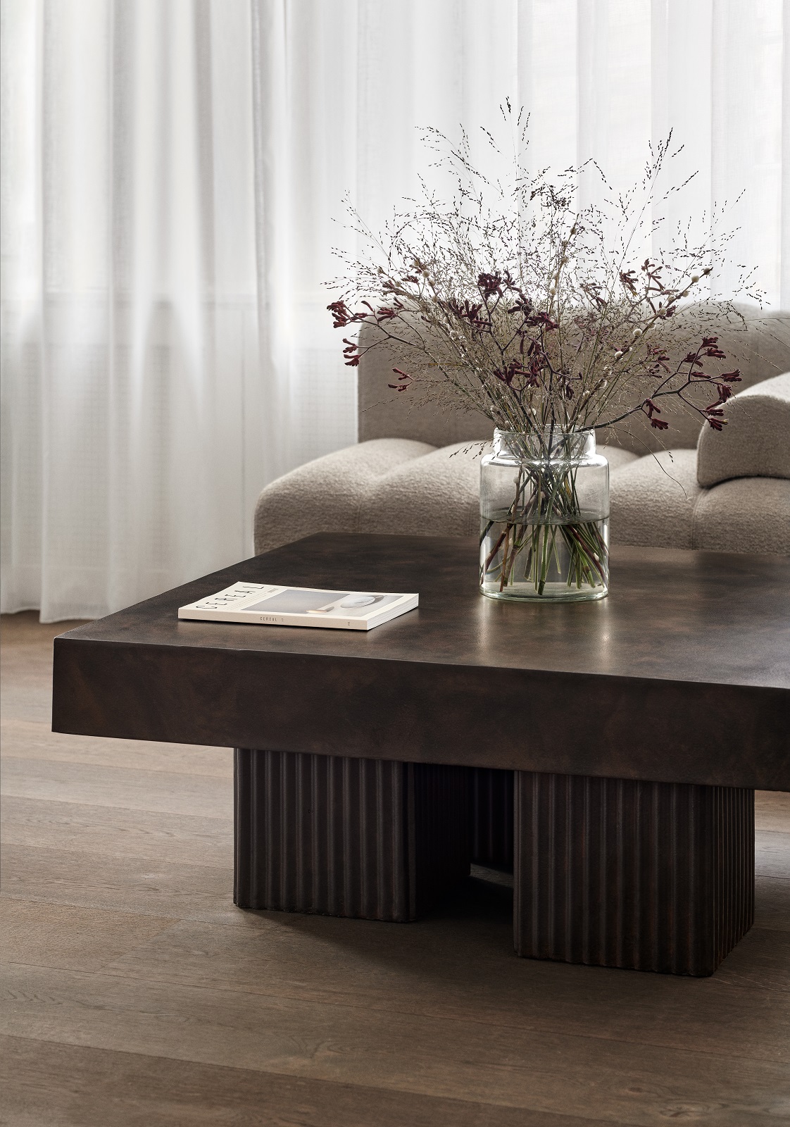 Norr11 Gear Square Couchtisch aus dunklem Holz mit geriffelten Beinen und Blumenvase im Wohnzimmer.