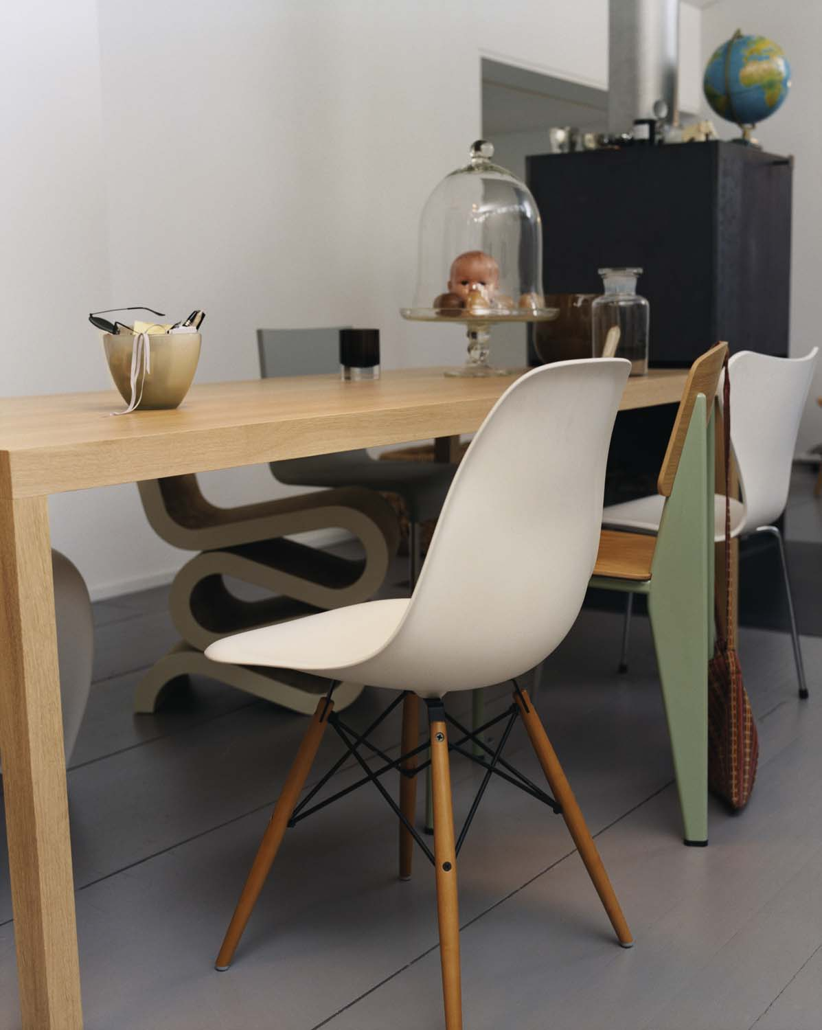 Weißer Eames Plastic Side Chair DSW Stuhl von Vitra am Esstisch, skandinavisches Designmöbel mit Holzbeinen.