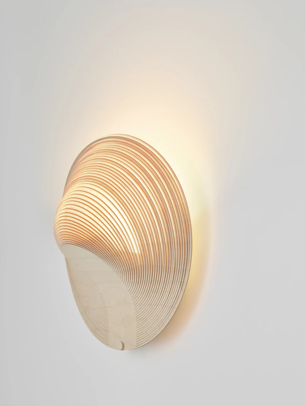 Illan Wandleuchte von Luceplan: Moderne Designleuchte aus Holz, die warmes Licht an die Wand wirft.