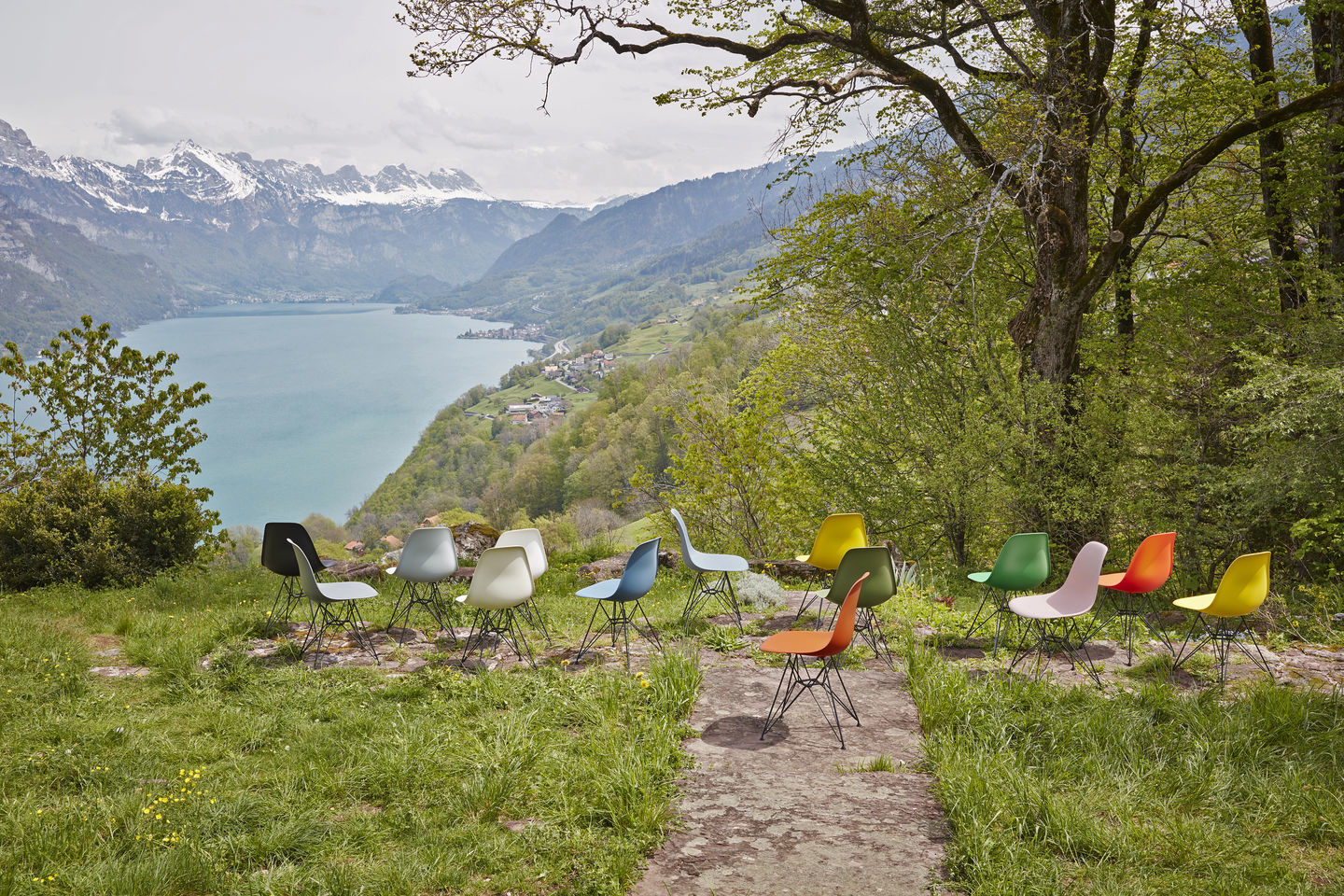 Eames Plastic Arm Chair DAR Stuhl Vitra Verchromt in Kieselstein und anderen Farben vor Bergpanorama.