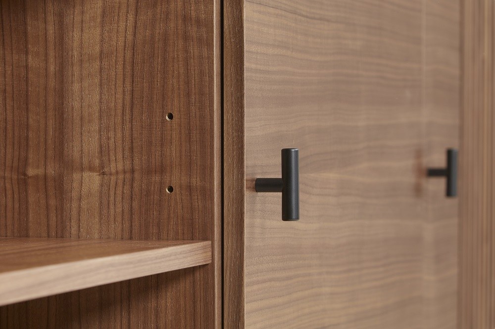 Detailaufnahme: Array Sideboard aus Walnuss von Woud mit schwarzen Griffen und Regalböden.