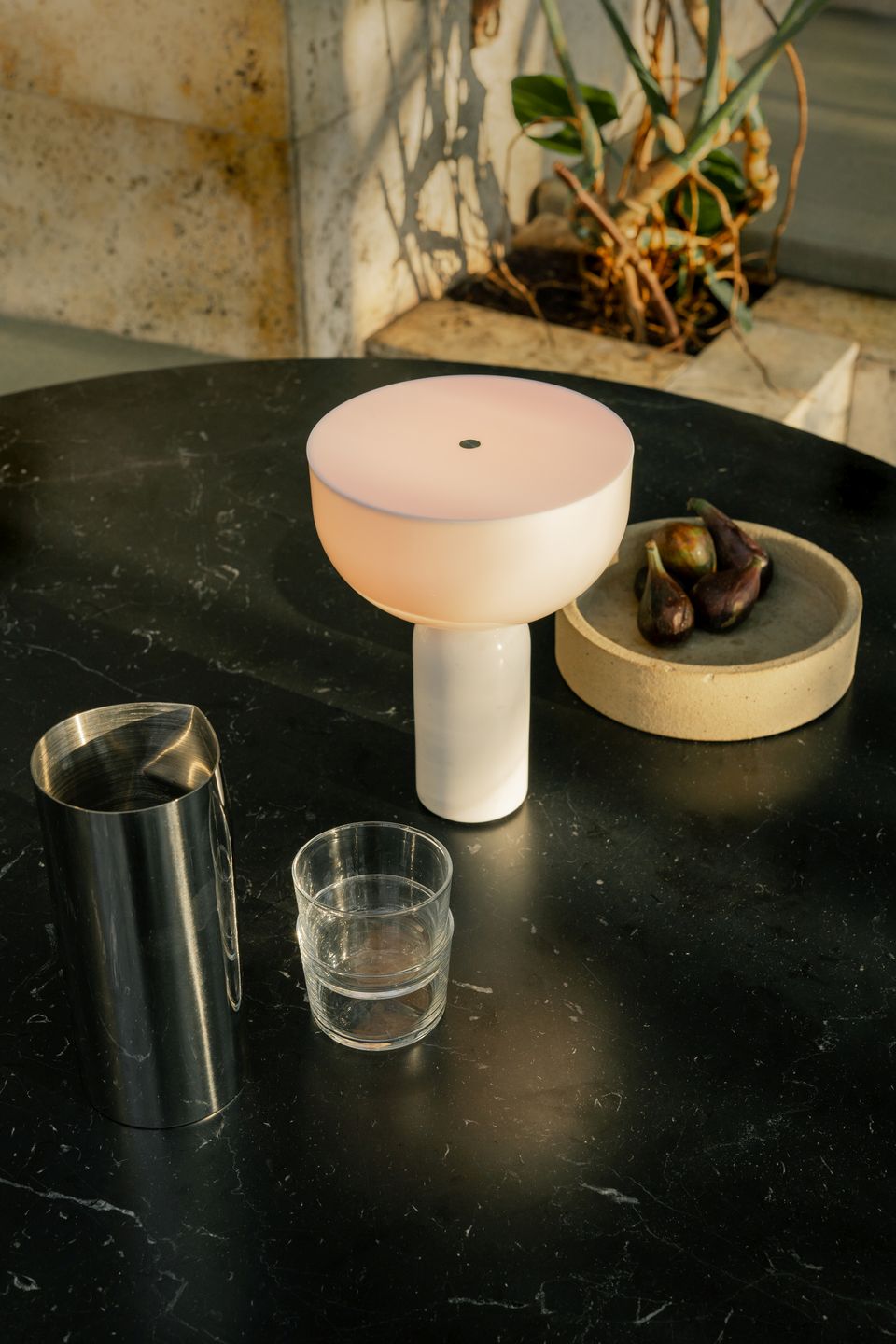 Kizu Tischleuchte von New Works, eine kabellose Akkuleuchte in Weiß auf einem dunklen Tisch.