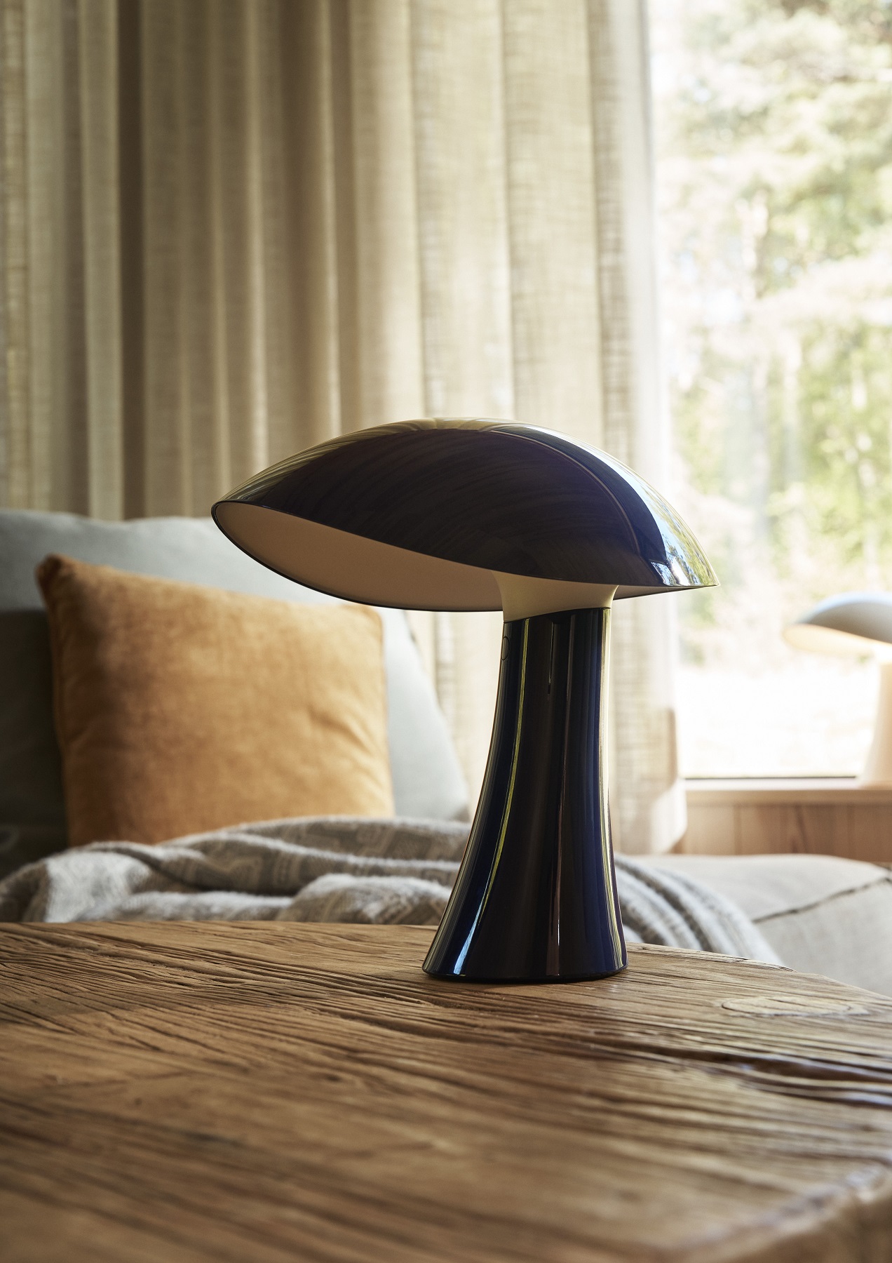 Rumee Akkuleuchte von Louis Poulsen, portable Tischleuchte für Innen und Außen auf einem Holztisch.