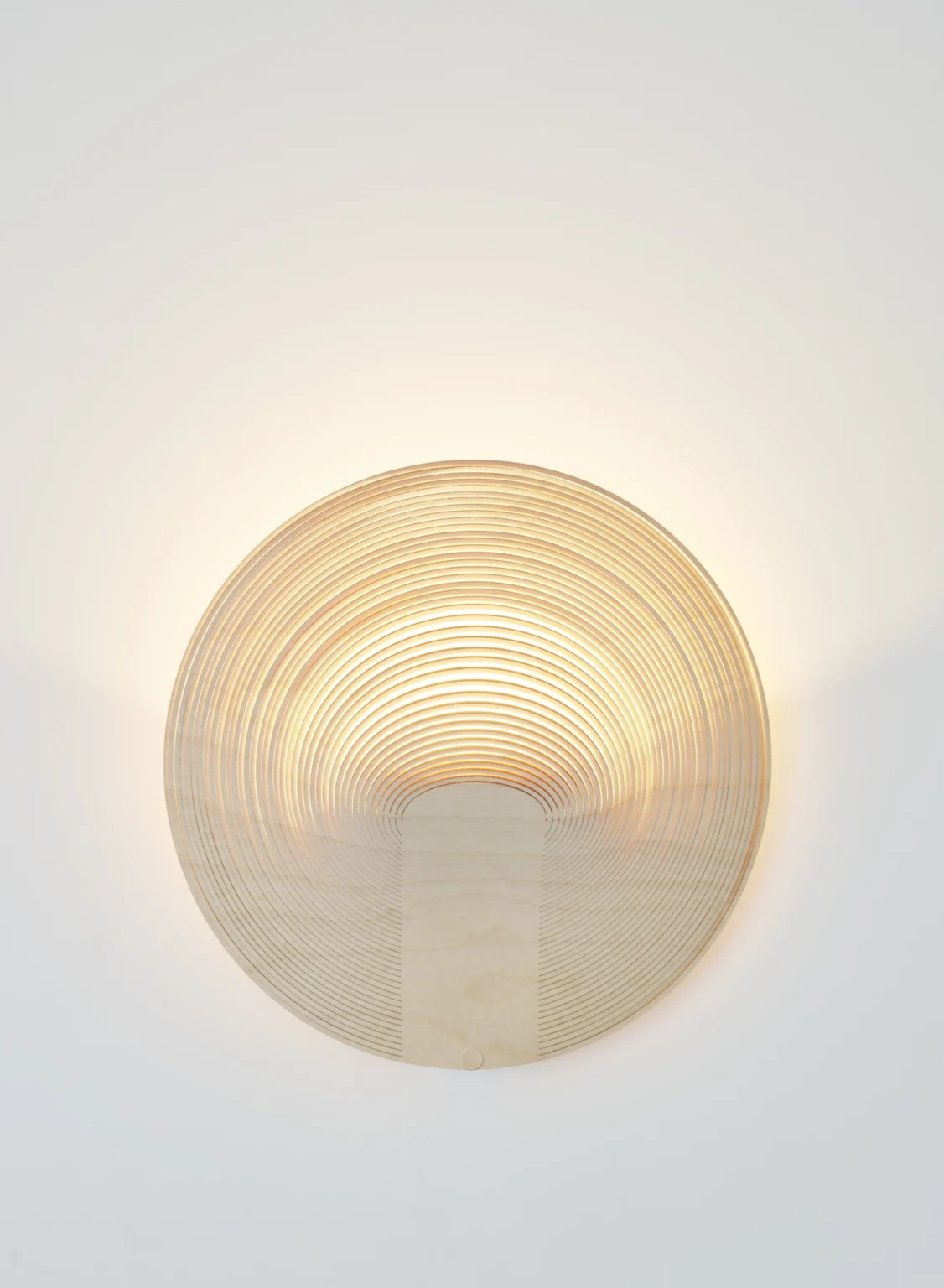 Illan Wandleuchte von Luceplan: Runde, moderne Designleuchte aus Holzfurnier an einer weißen Wand.