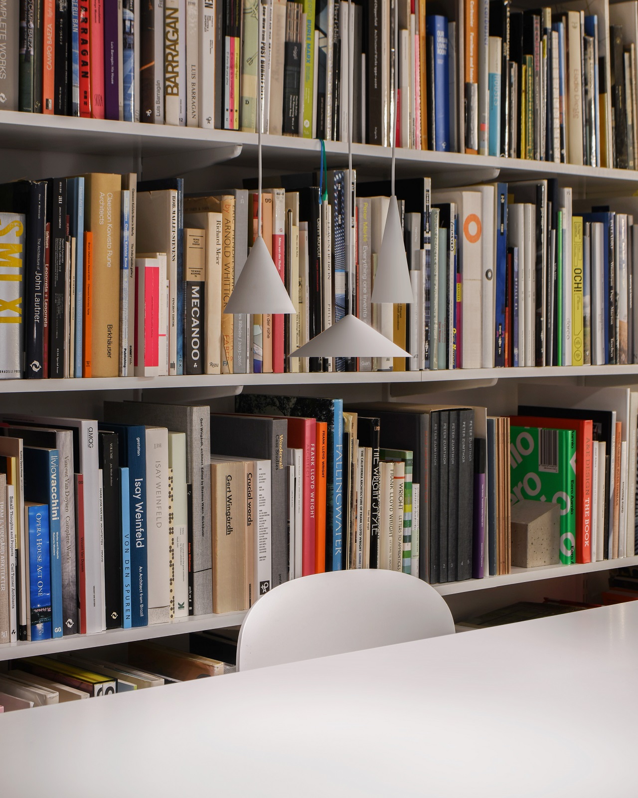 Nahaufnahme von drei grauen w201 S3 Pendelleuchten von wästberg vor Bücherregal.