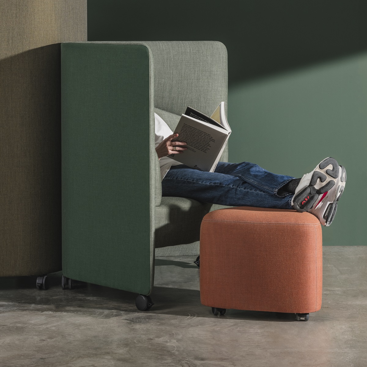 Person liest in grüner In Out Office Sitzgelegenheit mit Füßen auf orangefarbenem RS2264 Ottoman Hocker.