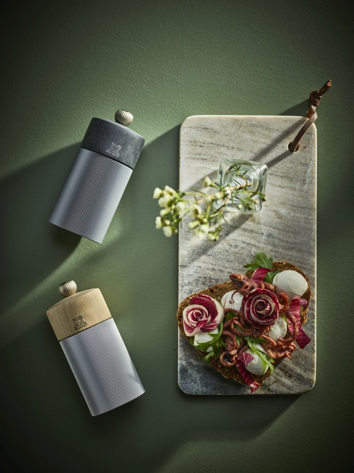 Produktfoto: Peugeot Line Salzmühle aus Aluminium und Naturholz, 12 cm hoch, neben Brotzeit auf Marmorbrett.