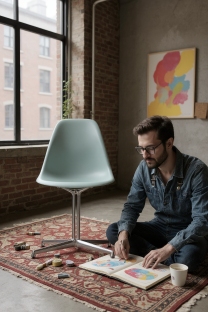 Eames Fiberglass Stuhl DSL von Vitra in Hellblau vor Fenster und rotem Backstein.