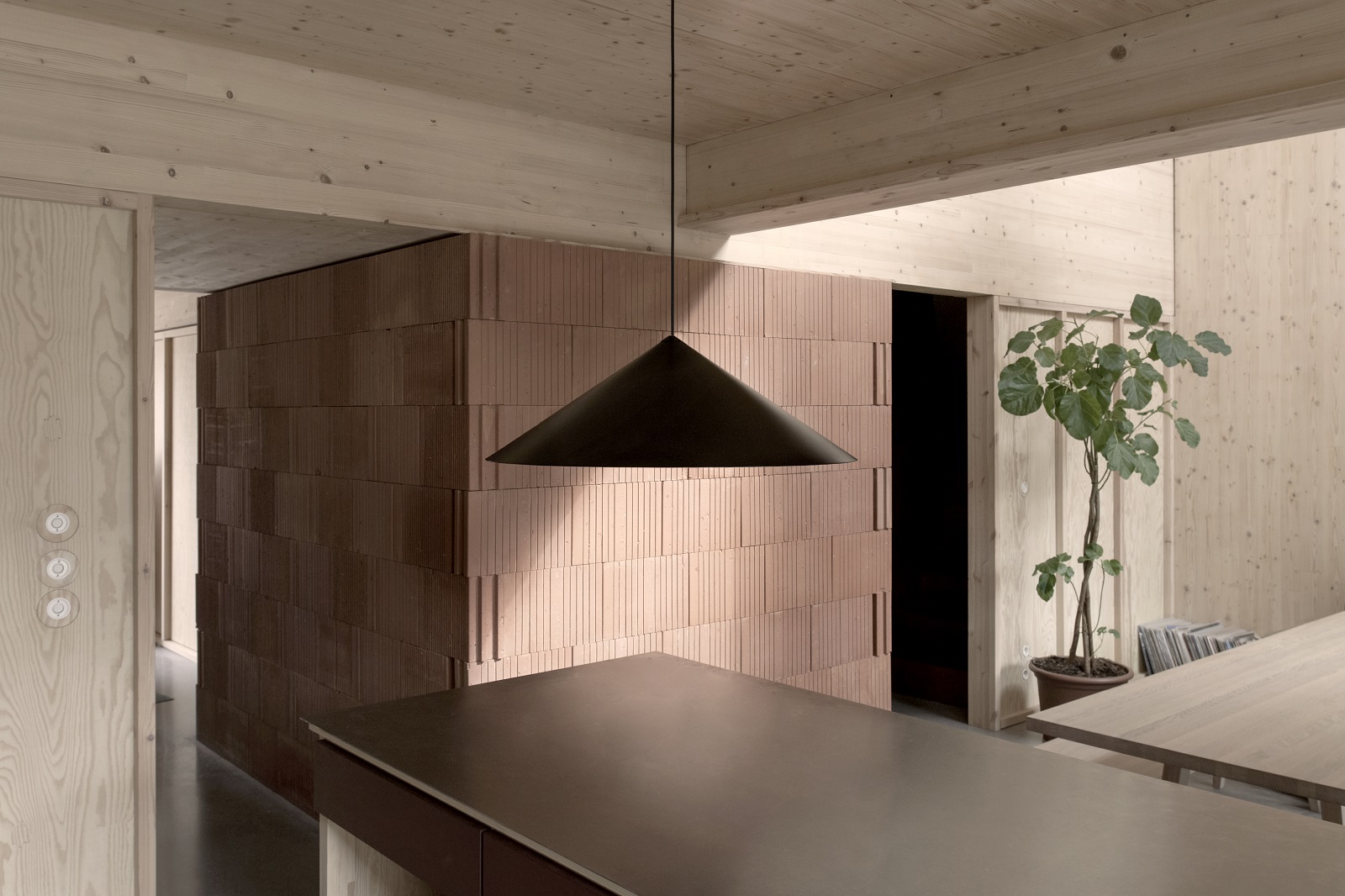 w221 S3 Medium Pendelleuchte von wästberg in modernem Interieur mit Holzwänden und Backsteinmauer.