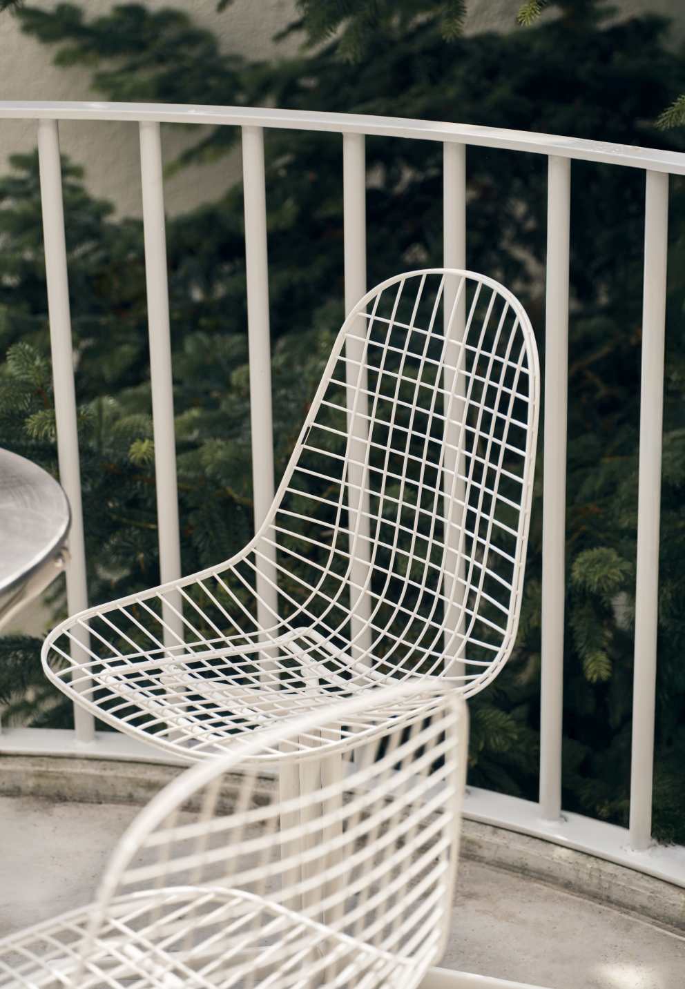 Nahaufnahme eines weißen, ungepolsterten DKL Wire Chair Stuhls von Vitra im Außenbereich.