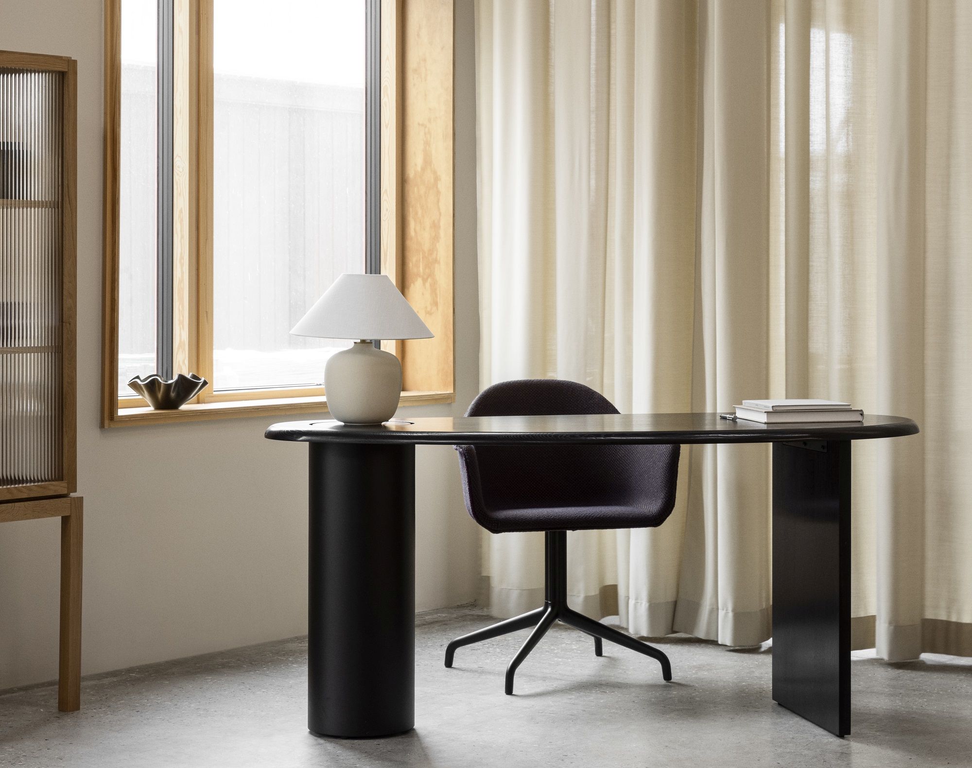 Audo Copenhagen Eclipse Desk Schreibtisch in Schwarz mit Stuhl und Lampe vor Fenster.