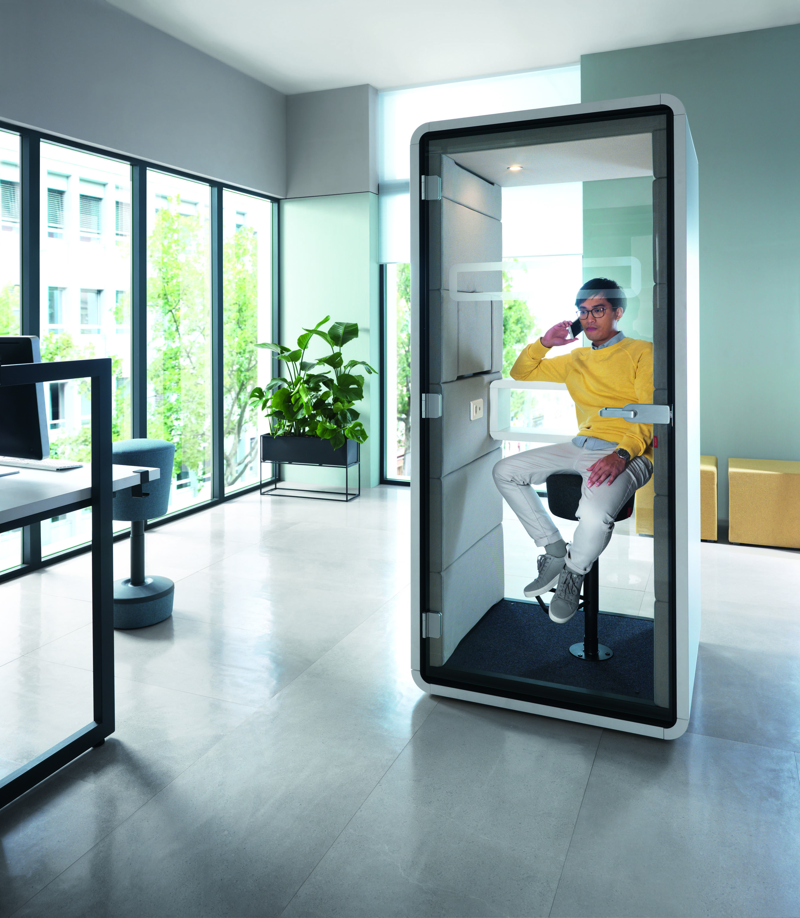 Mann telefoniert in einer HushPhone Meetingbox von Mikomax, einer schallisolierten Telefonzelle für Büros.