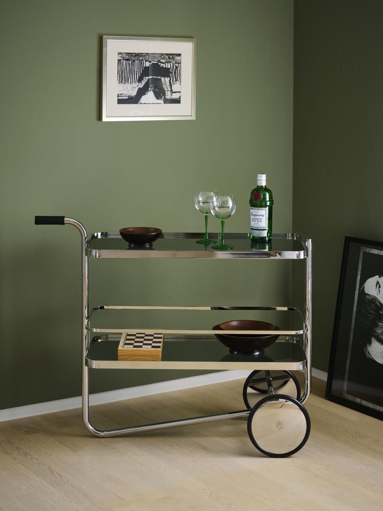 S 179 Tanqueray Barwagen Thonet mit Gin, Gläsern und Schale auf drei Ebenen vor grüner Wand.