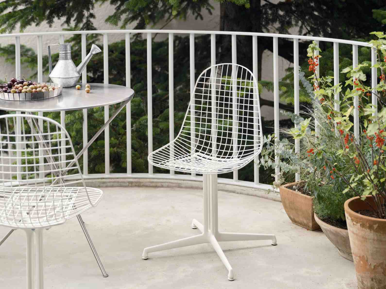 Weißer DKL Wire Chair Stuhl ungepolstert von Vitra auf einem Balkon mit Tisch und Pflanzen.