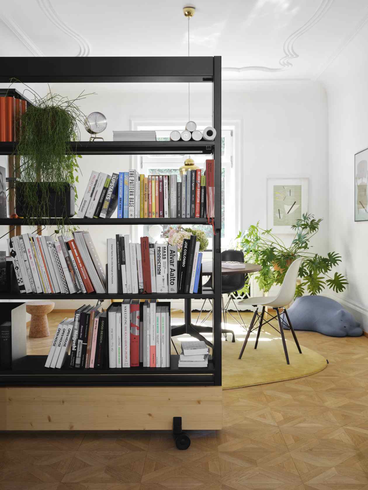 Nahaufnahme der Vitra Tripod Clock Tischuhr auf einem Regal in einem stilvollen Wohnraum.