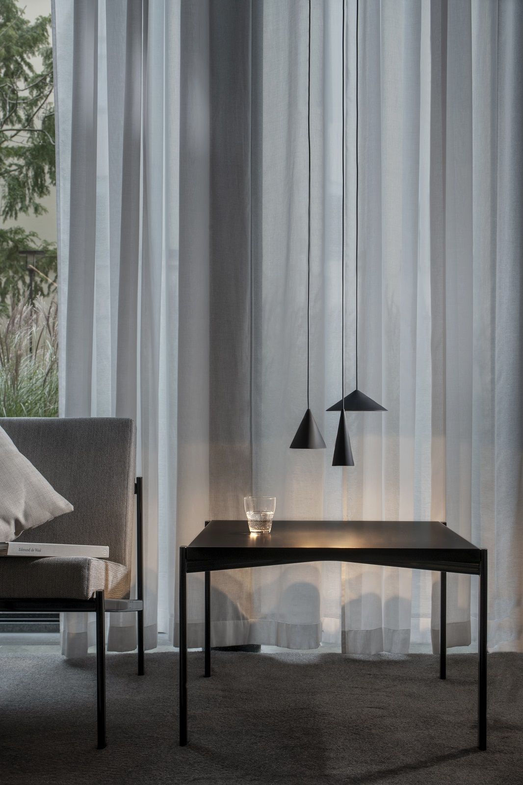Drei schwarze w201 S3 Pendelleuchten über einem Tisch, minimalistisches Design für Wohnzimmer und Esszimmer.