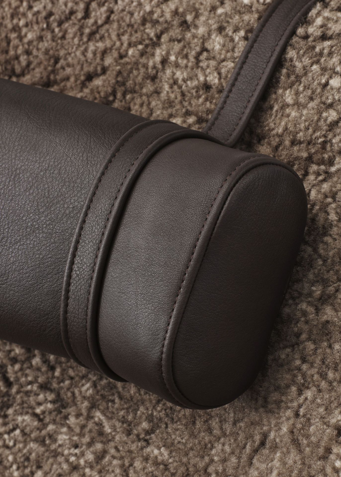 Braune Leder Nackenstütze von Lodge Vipp, Detailaufnahme auf einem Teppich. Komfort und Design.