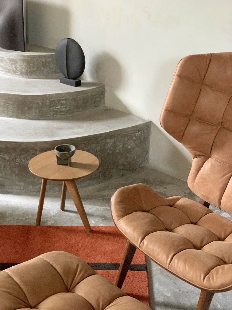 Nahaufnahme des NORR11 Mammoth Ottoman aus braunem Leder, kombiniert mit Beistelltisch und Sessel.