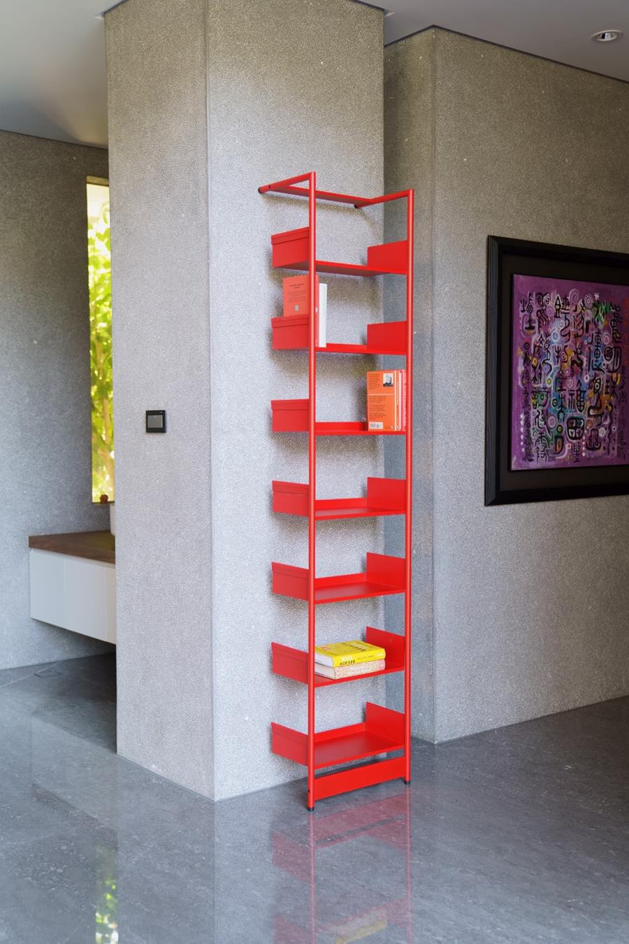 Rotes Pool 196 Anlehnregal von Mox mit Büchern und Boxen an einer grauen Wand.