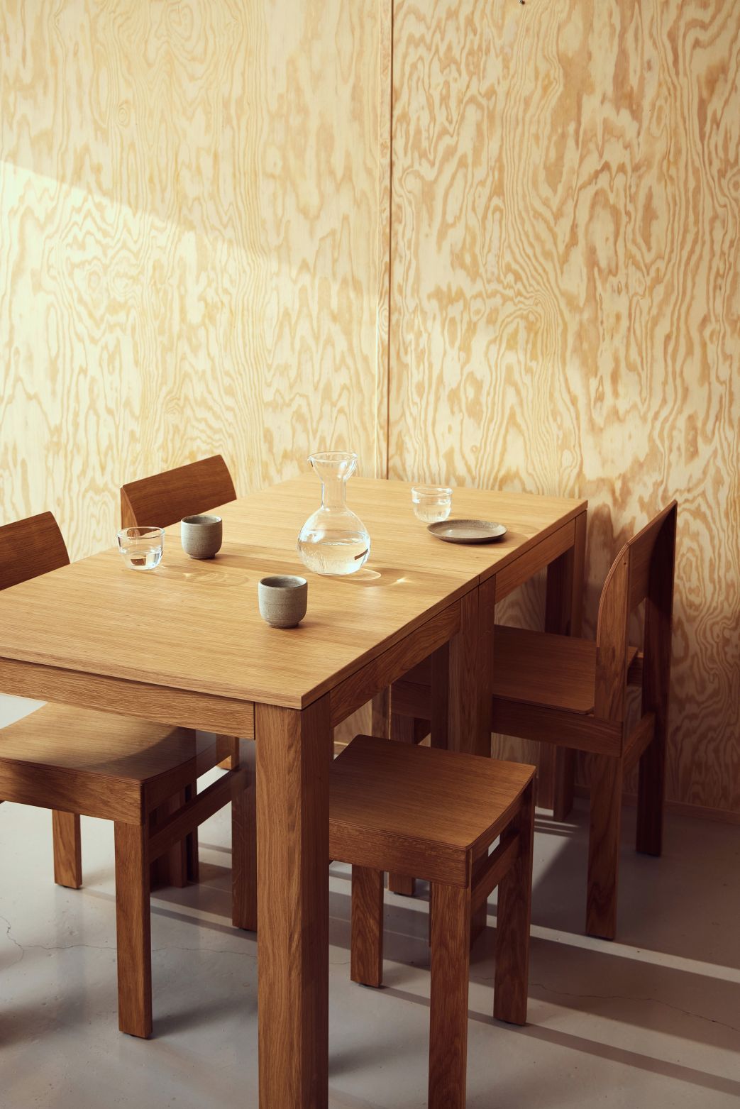 Sonder Hocker von Form & Refine aus Eichenholz, passend zum Esstisch mit Wasser Karaffe.