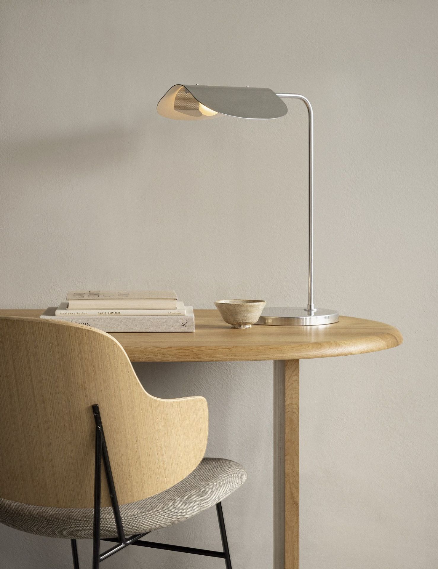 Audo Copenhagen Eclipse Schreibtischlampe aus Metall auf einem runden Holzschreibtisch mit Stuhl.