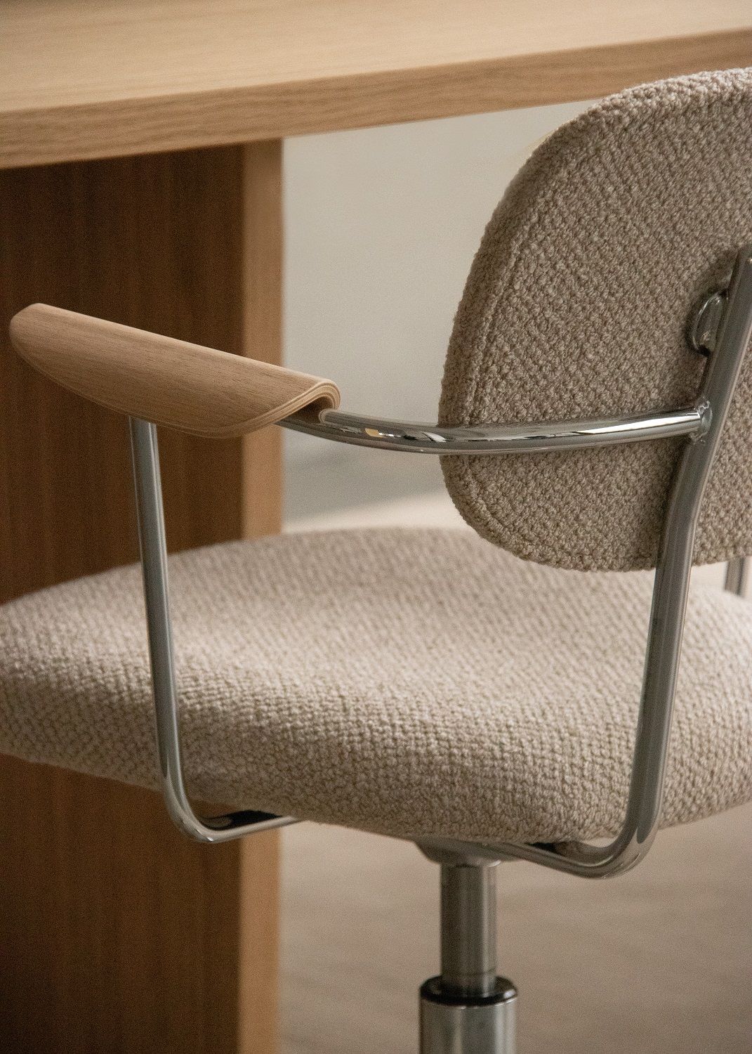 Detailaufnahme des Co Task Chair von Audo Copenhagen: Stoffbezug, Holzarmlehne und verchromtes Gestell.