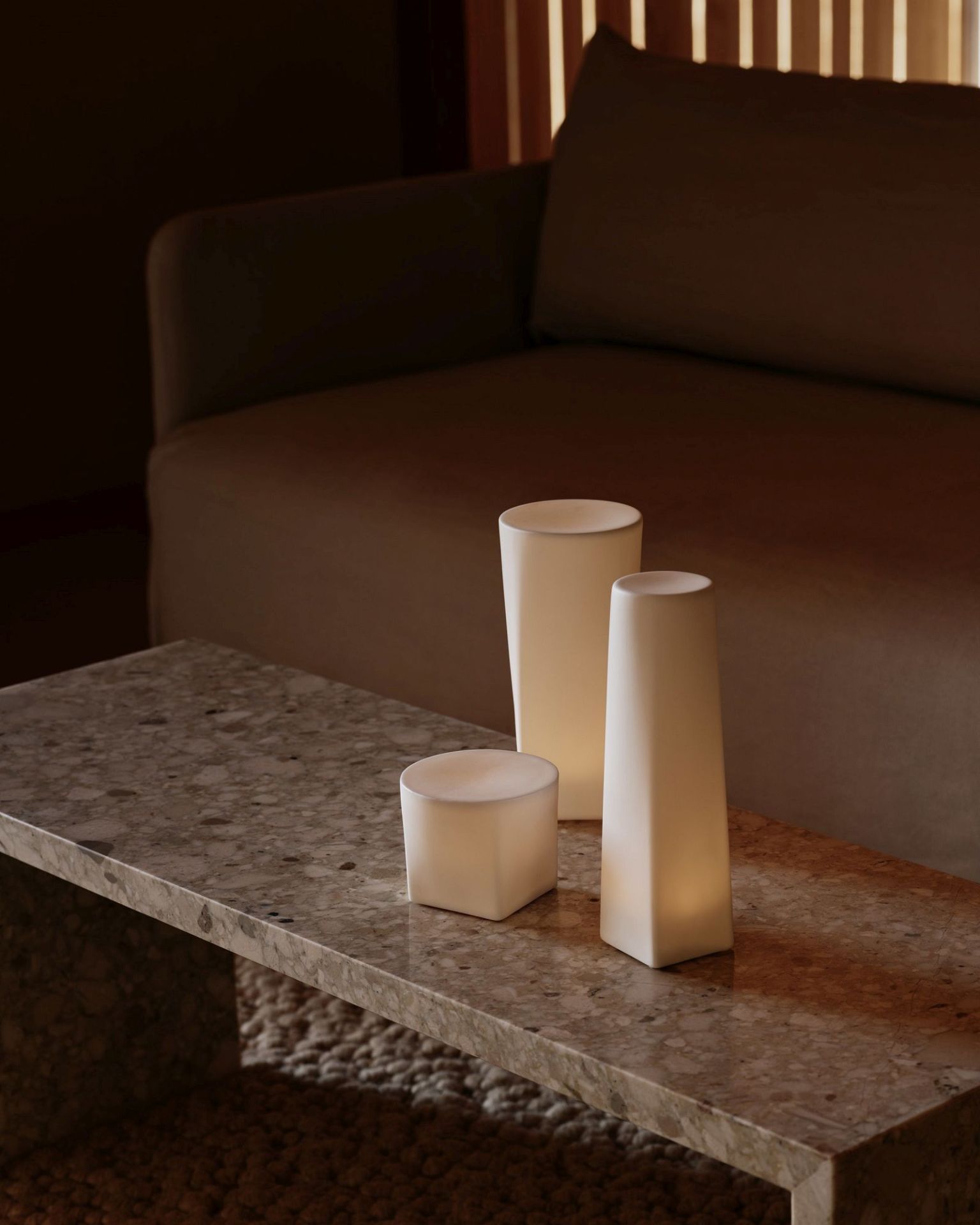 Audo Copenhagen Offset Sofa im Wohnzimmer mit minimalistischen Tischleuchten auf einem Marmortisch.