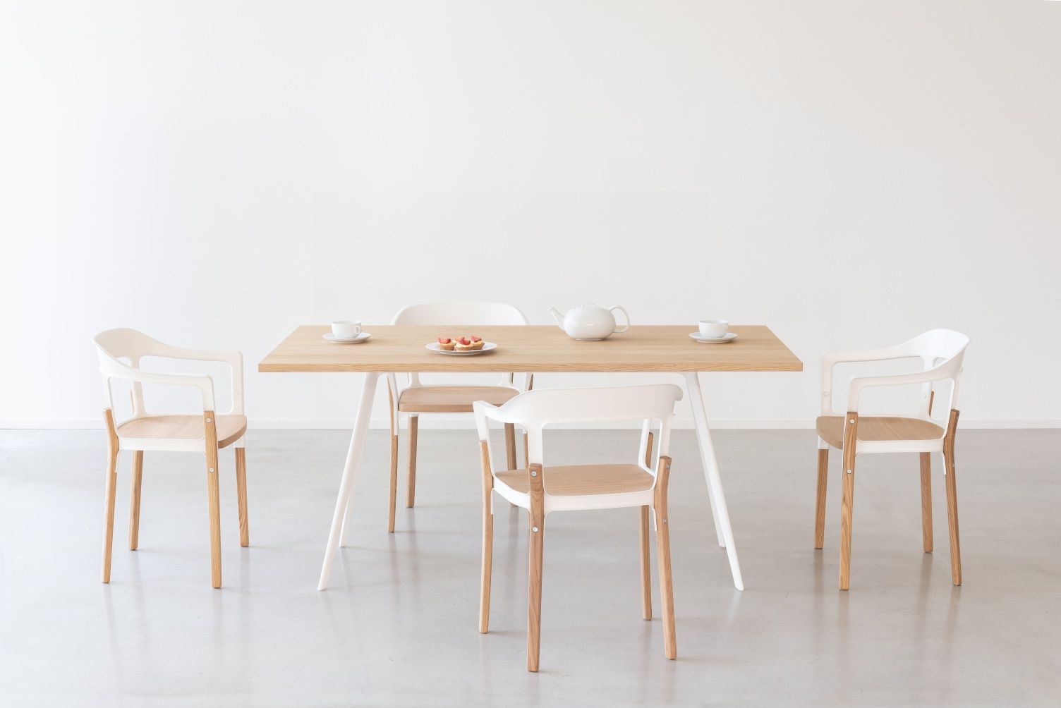 Esszimmer mit Holztisch und vier Magis Steelwood Stühlen mit weißen Kunststofflehnen und Holzbeinen.