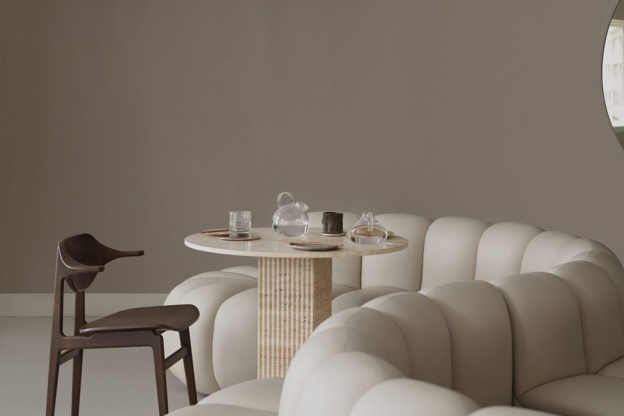 NORR11 Bufala Dining Chair aus Holz neben einem runden Tisch und einem modularen Sofa.